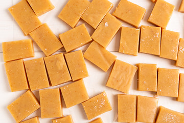 Fresh caramel fudge candies on white rustic background