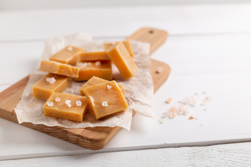 Fresh caramel fudge candies on white rustic background