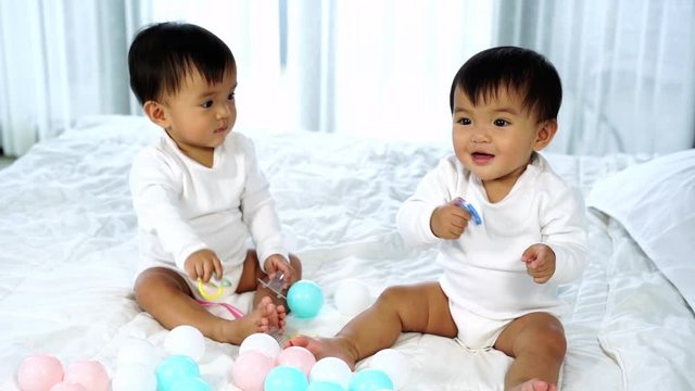 slow-motion of cheerful twin babies on a bed