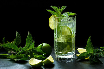 Mojito cocktail with lime and mint in  glass on black tray