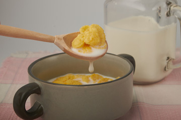 Bowl with Cornflakes and Milk on an wooden table