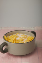 Bowl with Cornflakes and Milk on an wooden table