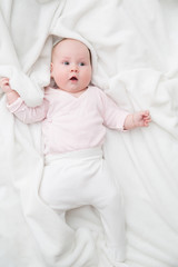 baby girl is lying on white blanket