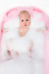 Happy little baby a swimming in the bathroom.Portrait of baby bathing in foam