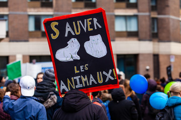 Ecological activists march for change. A French sign is seen closeup in a crowd of protestors saying save the animals as environmental demonstrators march on an urban city street.