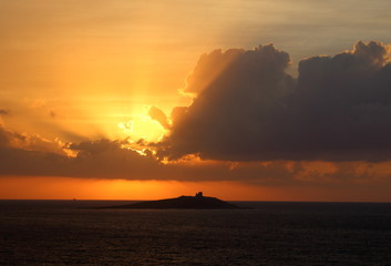 evocative image of sunset over the sea with island in the background