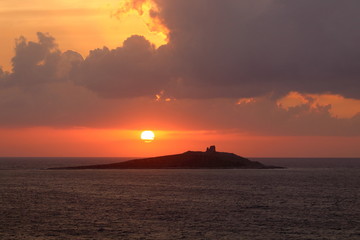 Naklejka na ściany i meble evocative image of sunset over the sea with island in the background