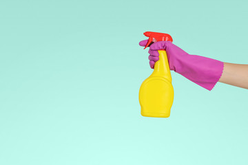 Hand in gloves holds spray bottle.