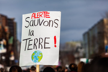 Eco demonstrator holds French sign. A closeup view of a French sign reading Alert, save the planet. Held by an ecological activist during a peaceful street protest.