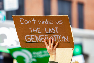 Ecological activists march for change. A cardboard sign is seen closeup in the hand of an...