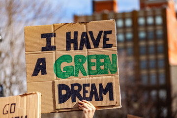 Ecological message at street rally. A protestor holds a cardboard sign, reading I have a green dream, viewed close-up as people unite against global warming in a city center.