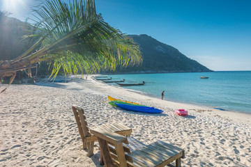 Tropical background from Phangan island in Thailand with beach chair on the sand  with blue sky and palm trees. Travel Vacation concept