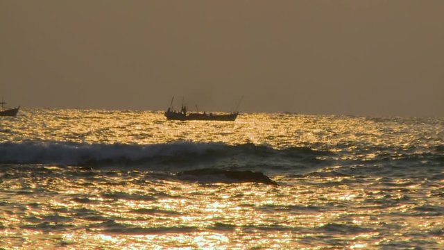 Wide low-angle still shot of local fishing boats at the sea at sunset, Ngapali Beach, Myanmar
