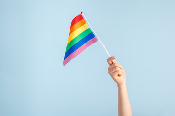 Gay flags in women's hand on grey background