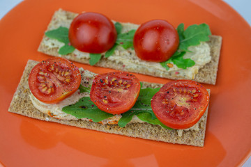 Rye crisps with cherry tomatoes, arugula and hummus. Delicious healthy vegan snack.