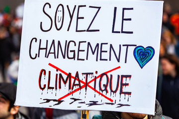 French banner at eco activism march. A close up view of a French poster, saying be climate change, held by an ecological activist during an environmental rally on an urban city street.