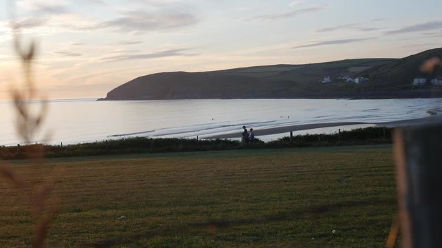 Croyde Bay in North Devon. A group of people can be seen walking on the coast path above the beach.