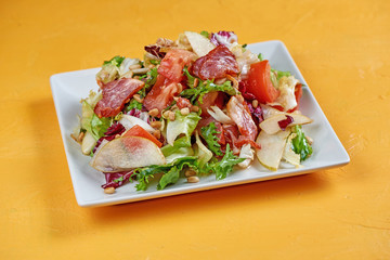 Salad with pear, proshutto, grapes, arugula, soft cheese and nuts. Salad of autumn