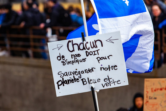 French sign at climate change rally. A French placard reads each of us must get involved to safeguard our blue and green planet, seen closeup as environmentalists rally against global warming