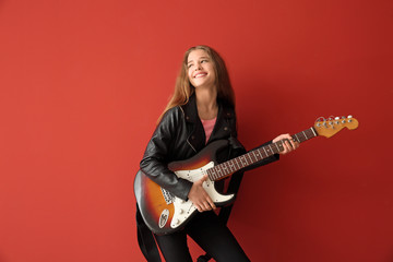 Teenage girl playing guitar against color background