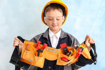Cute little boy with tools belt on color background