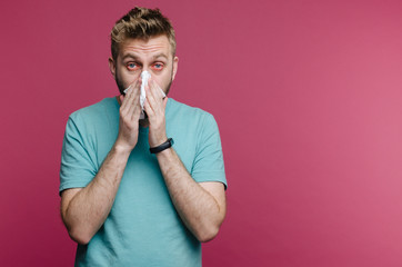 studio picture from a young man with handkerchief. Sick guy isolated has runny nose. man makes a...