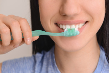 Woman with toothbrush on light background, closeup. Concept of dental hygiene