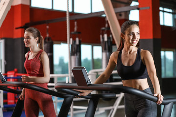 Sporty young women on treadmills in gym