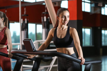 Fototapeta premium Sporty young woman on treadmill in gym