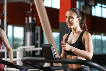 Fototapeta na wymiar Sporty young woman on treadmill in gym