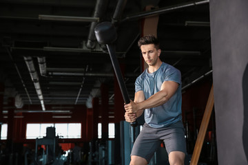 Obraz na płótnie Canvas Sporty young man training with tire in gym