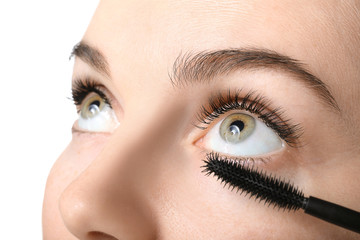 Naklejka premium Beautiful young woman with eyelash extensions applying mascara against white background, closeup