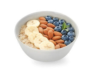 Bowl with tasty oat porridge, blueberry, banana and nuts on white background