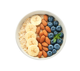 Bowl with tasty oat porridge, blueberry, banana and nuts on white background