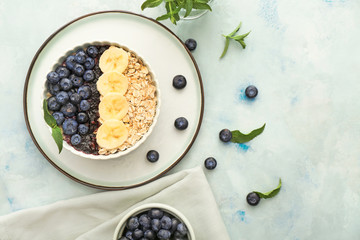 Bowl with tasty oat flakes, blueberry and banana on table