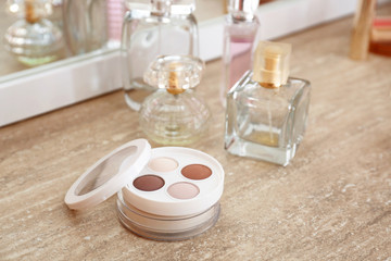 Makeup cosmetics with bottles of perfumes on dressing table