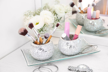 Makeup cosmetics with jewelry and brushes on dressing table