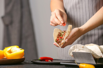 Woman preparing tasty fresh tacos in kitchen