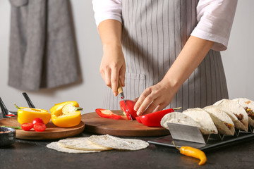 Woman preparing tasty fresh tacos in kitchen