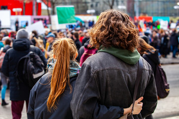 People gather for climate change. Two young people are seen from the back, watching a crowded...