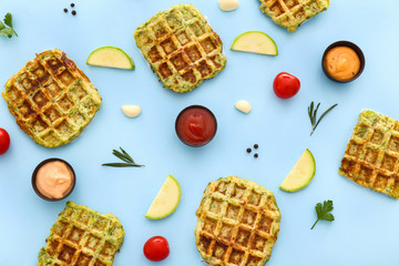 Tasty squash waffles with sauces on color background