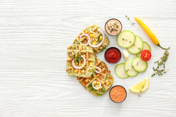Tasty squash waffles with sauces on white table