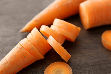 Sliced fresh carrots on wooden background, closeup