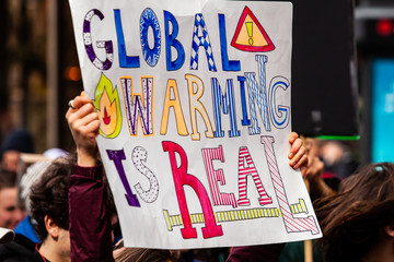 Homemade sign at environmental rally. A colorful poster is viewed closeup, saying global warming is...