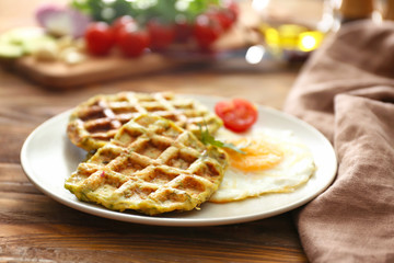 Plate with tasty squash waffles and fried egg on wooden table