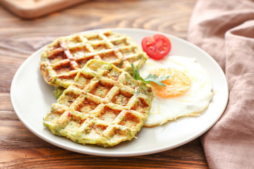 Plate with tasty squash waffles and fried egg on wooden table