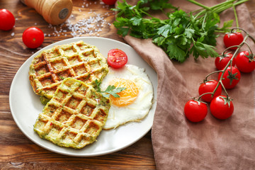 Plate with tasty squash waffles and fried egg on wooden table