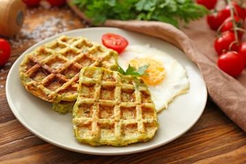 Plate with tasty squash waffles and fried egg on wooden table