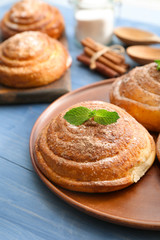 Plate with tasty cinnamon buns on wooden table