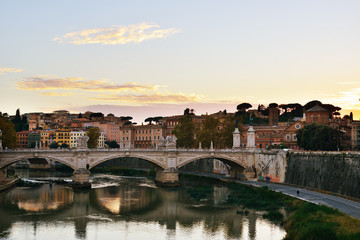 Fototapeta na wymiar The eternal City. Embankment of the Tiber river and the view of the majestic Rome (Italy) with its bridges and beautiful architecture at sunset.